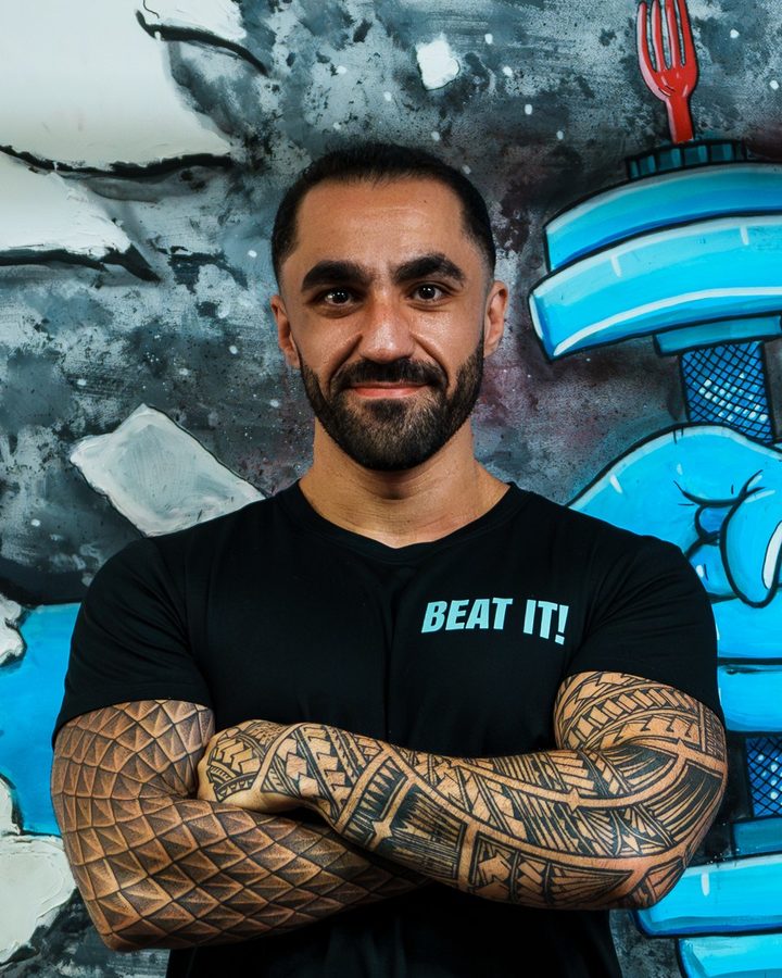 Jason, a coach, smiling in front of the Beat It mural