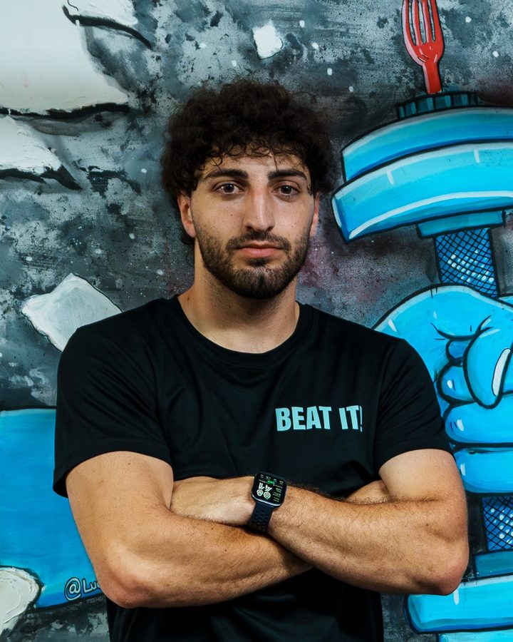 Zak, a coach, in a black Beat It T-shirt in front of the mural