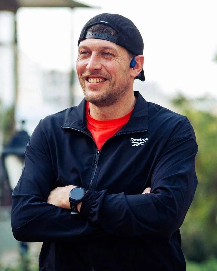 Brian, the running coach, smiling outdoors in a cap and black jacket