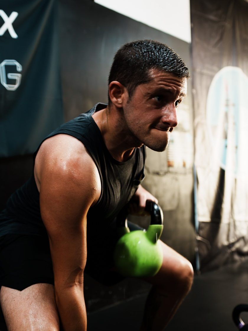 A member lifting a green kettlebell from the floor