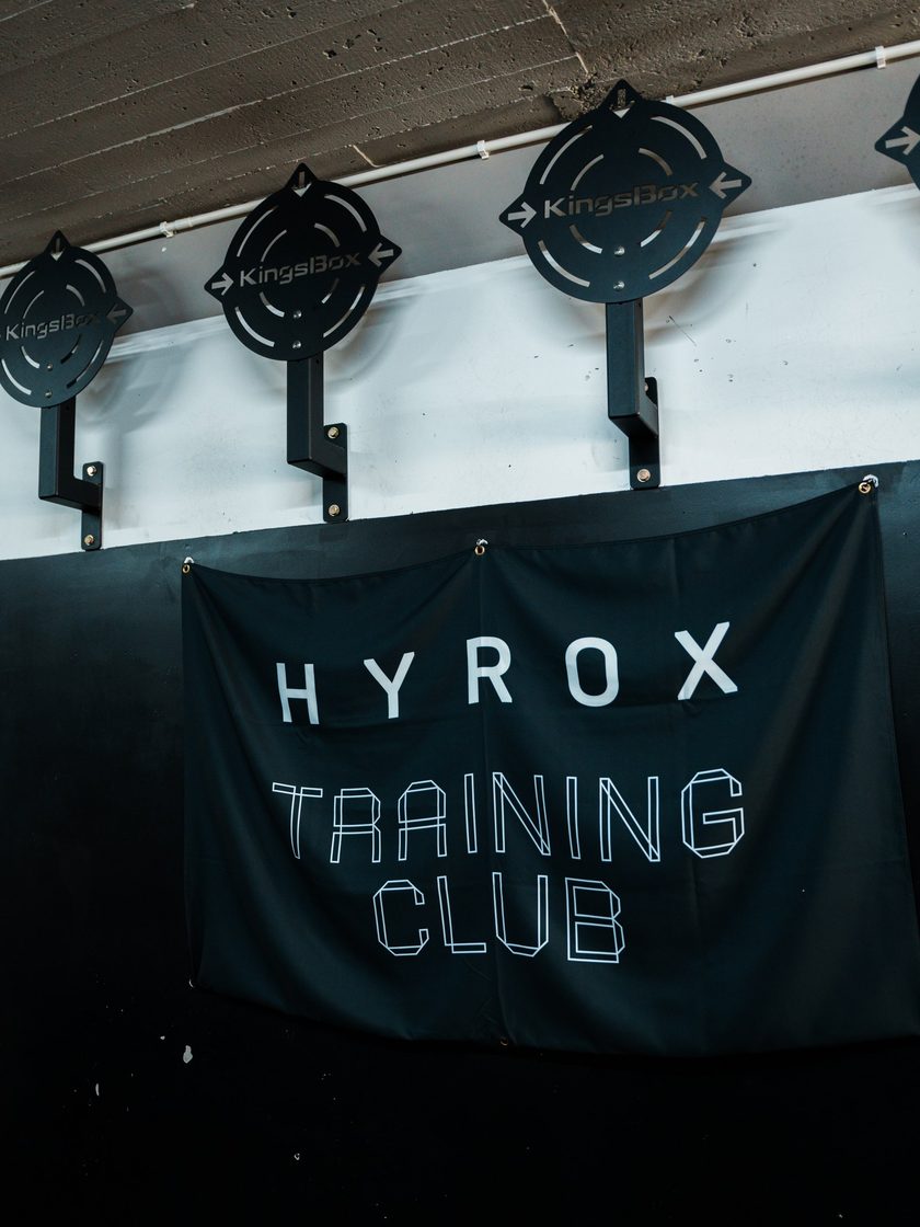 The HYROX Training Club banner on the gym wall under the wall-ball targets