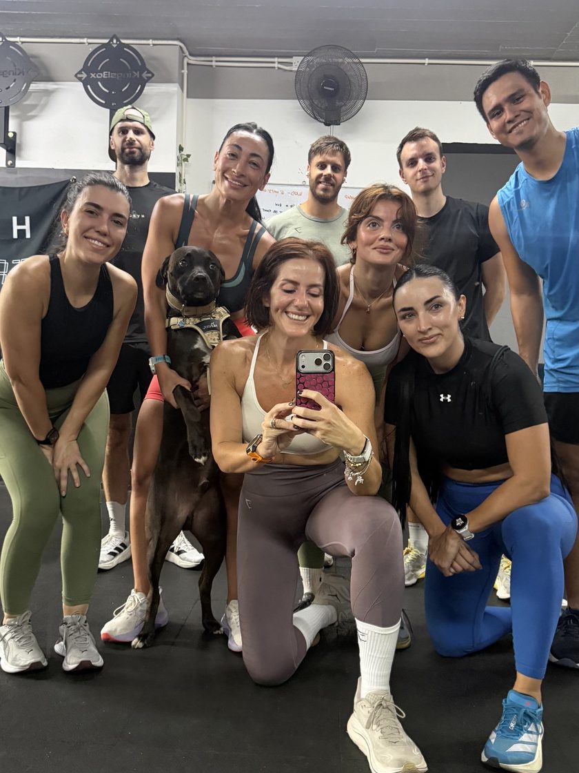 Members and a dog posing for a group selfie on the gym floor