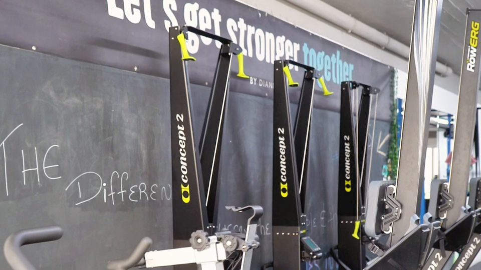 Concept2 rowers in a row under the gym's chalkboard wall